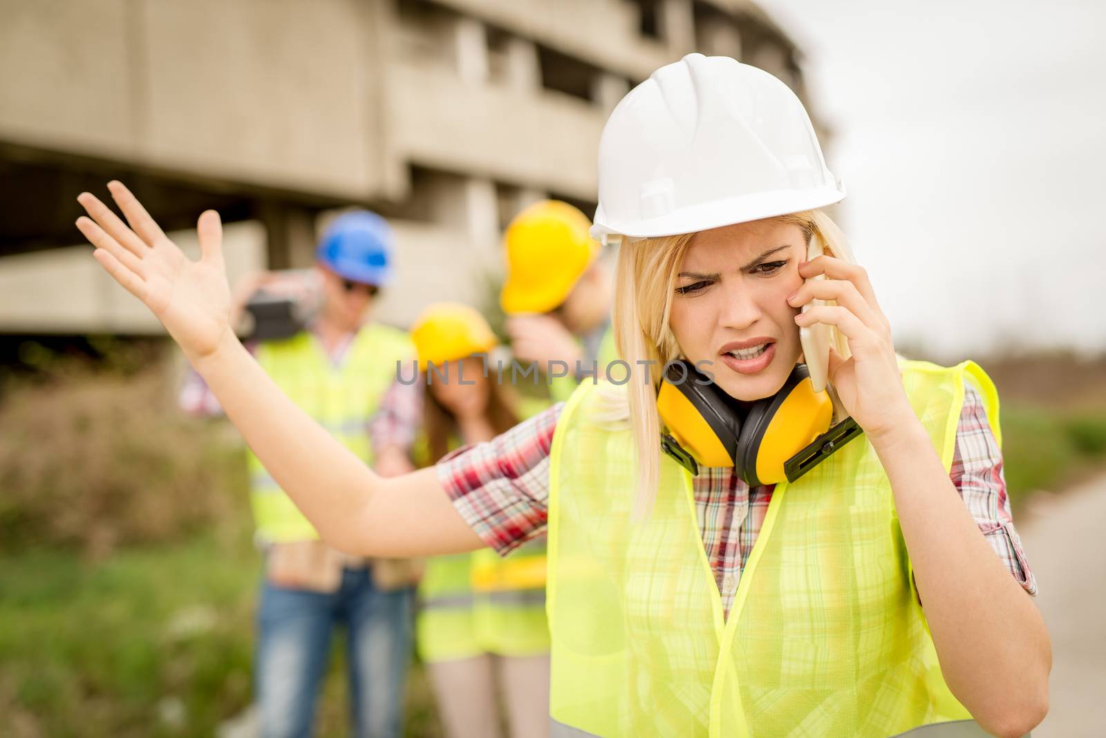 Beautiful young female construction architects using phone in front building damaged in the disaster.