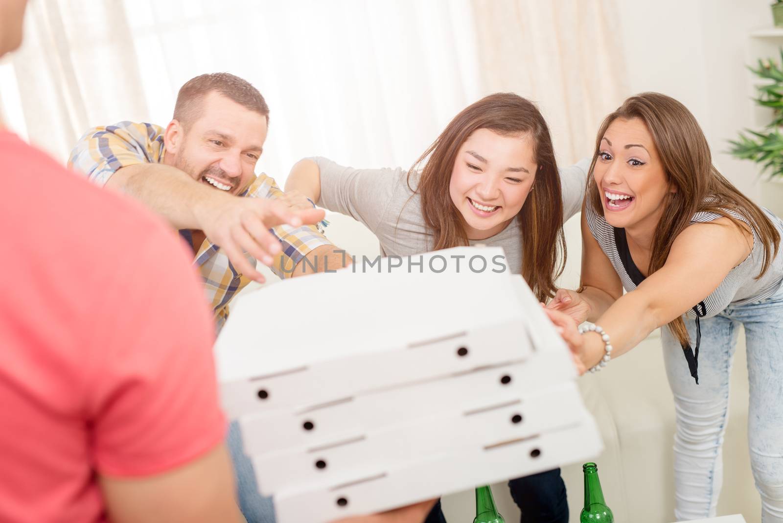 Four cheerful friends enjoying pizza together at home party. Selective focus.