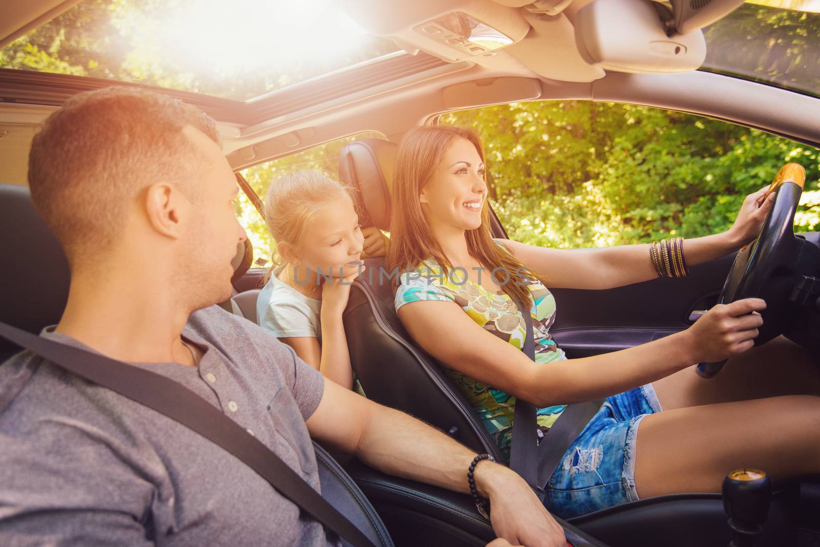 Beautiful family of three enjoying at driving a car and going on road trip.