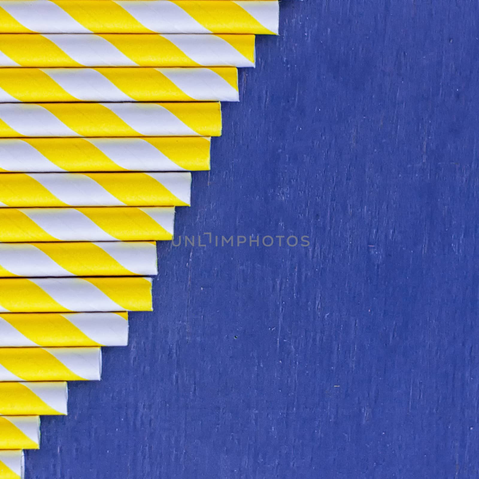 Striped straws for cocktails on blue wooden background