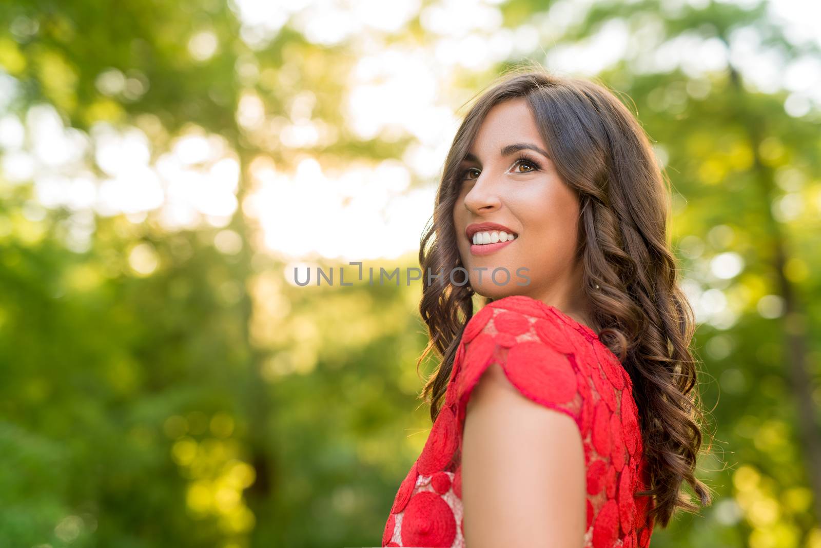 Portrait of young beautiful woman in red dress posing in the park.