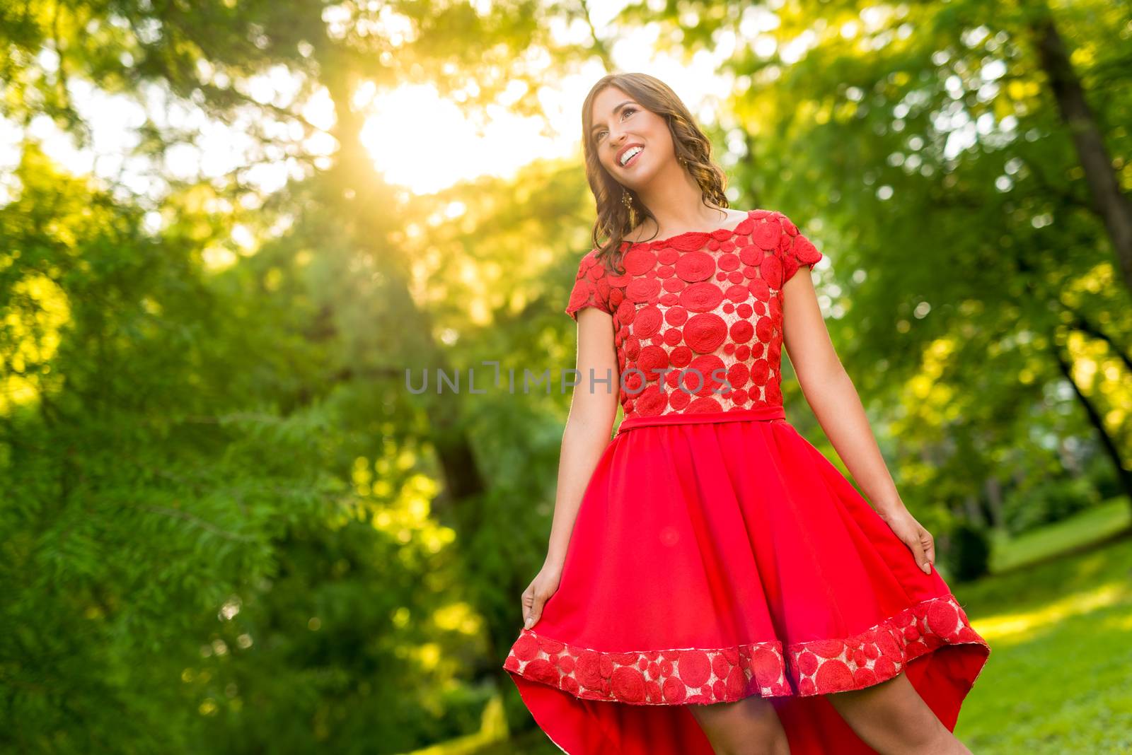 Young beautiful woman in red dress posing in the park.