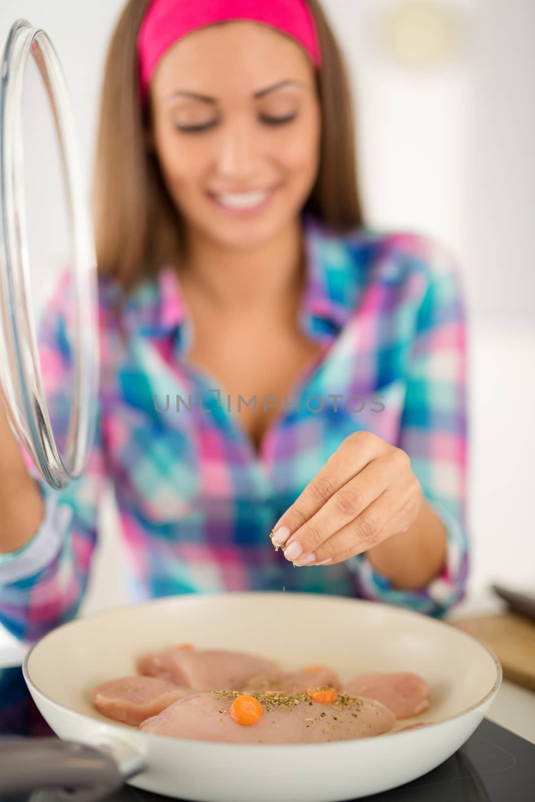 Beautiful young woman cooking healthy meal in the domestic kitchen. Selective focus. Focus on foreground, on meat.
