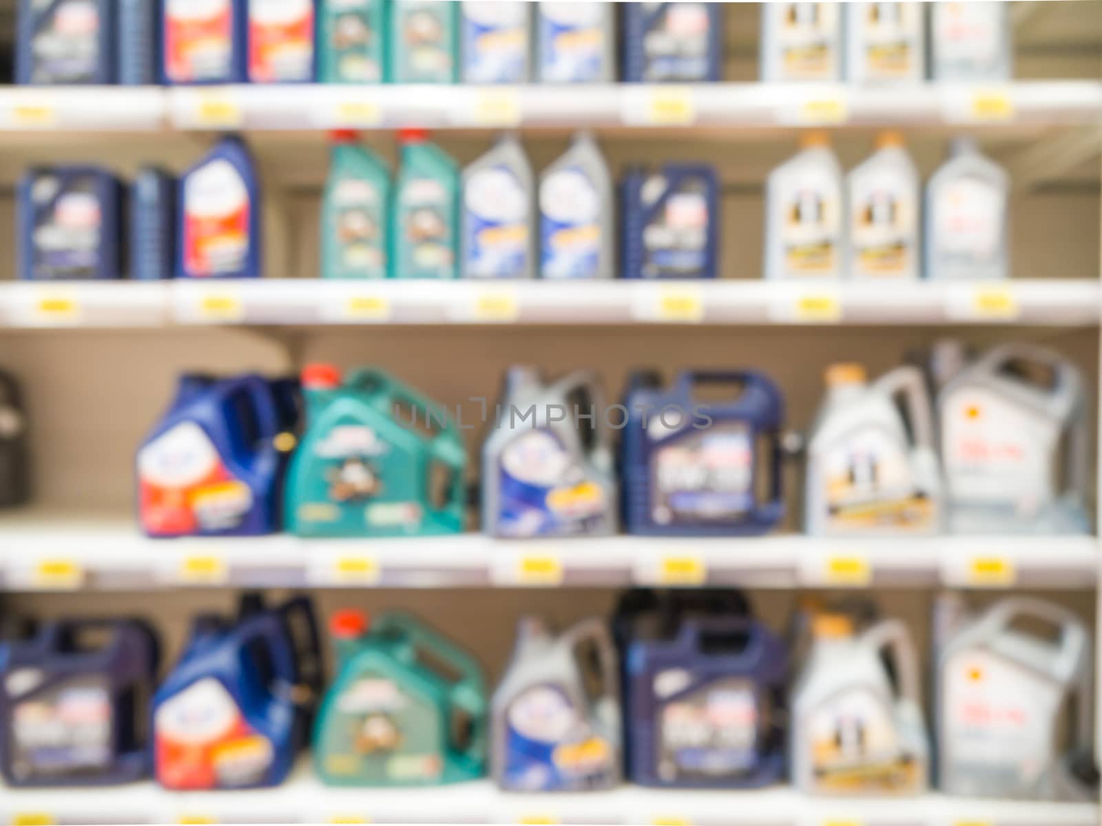 Blurred colorful motor oil bottles on shelves in supermarket as background