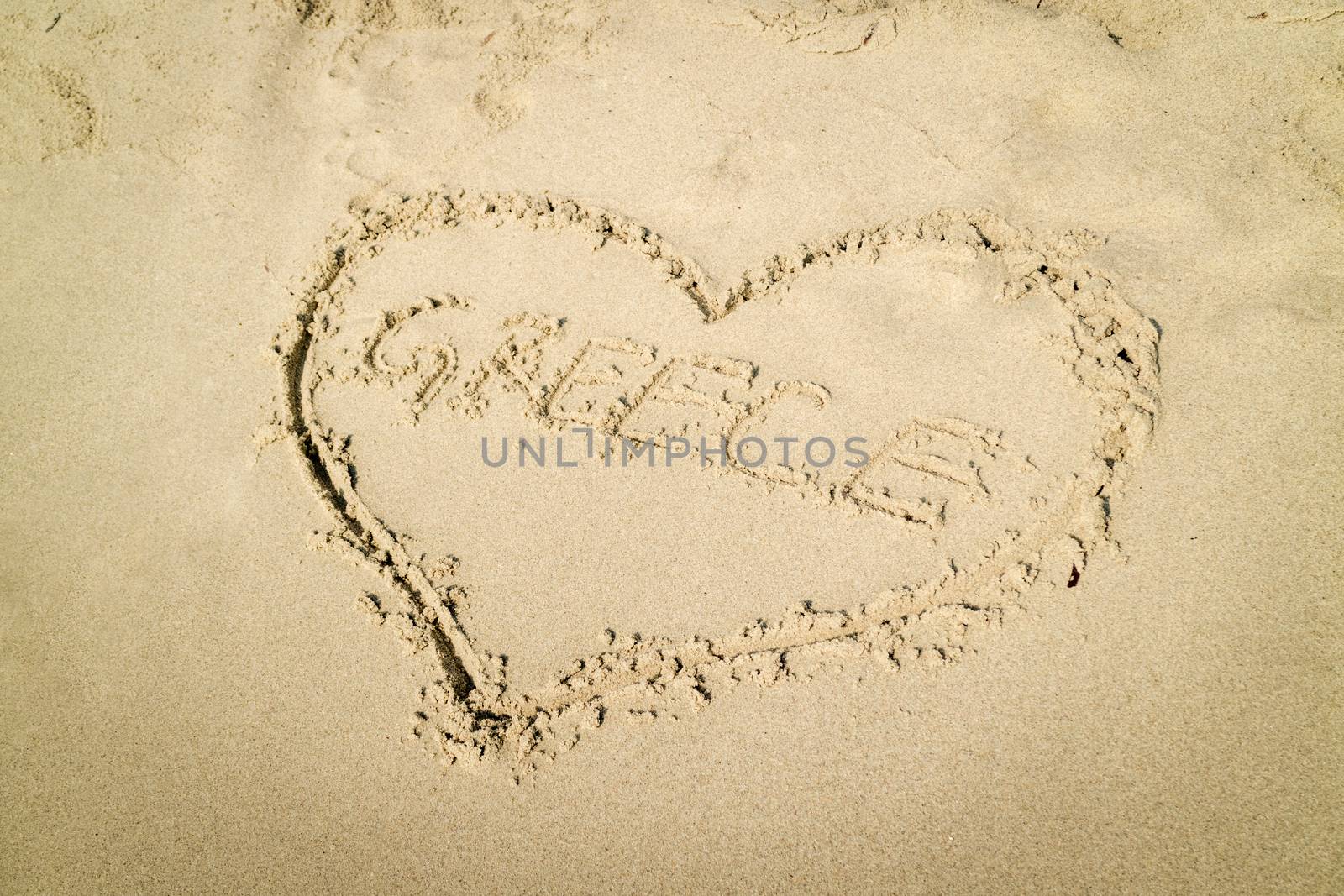 Heart shaped word Greece written on the sandy beach.