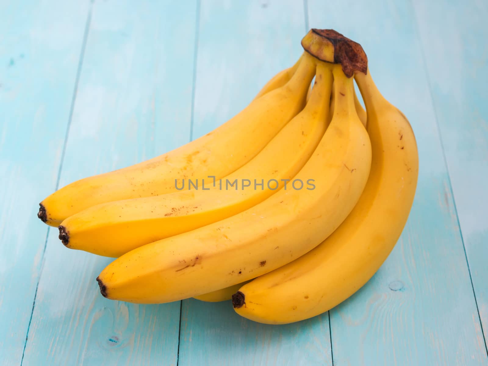 Colorful bananas on blue wooden table background