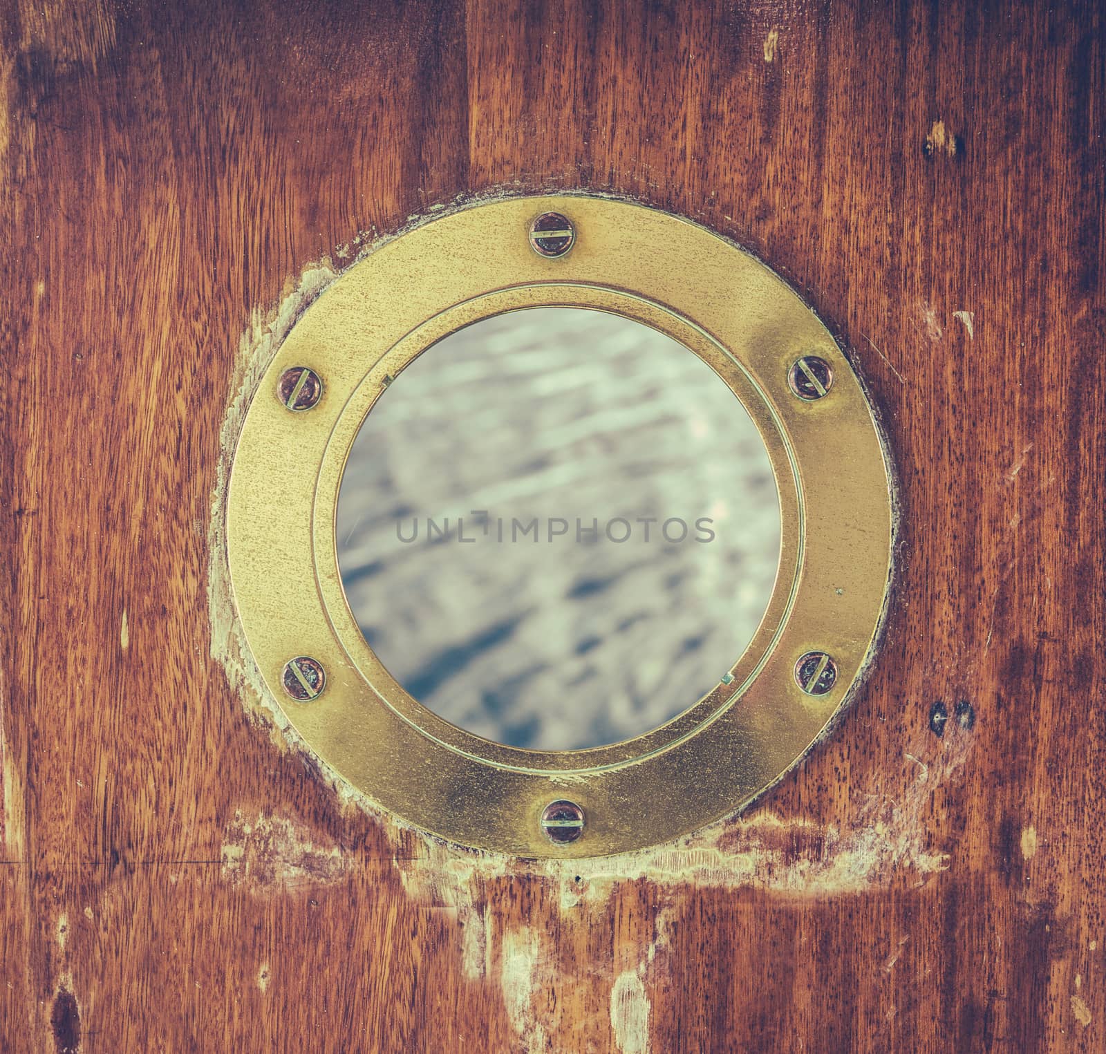 A Vintage Brass Or Bronze Porthole In A Ship's Door With Ocean Water Visible