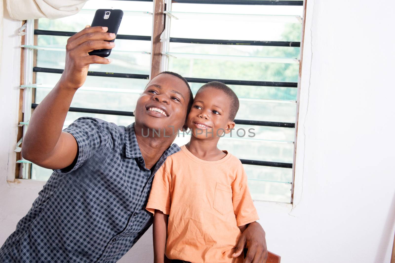 Father and son are very happy to take pictures with his mobile phone.