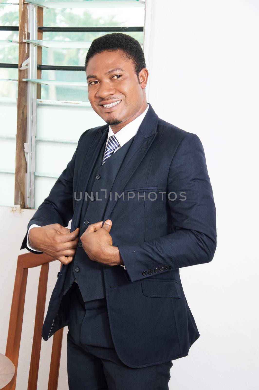 young businessman standing in his office and smiling