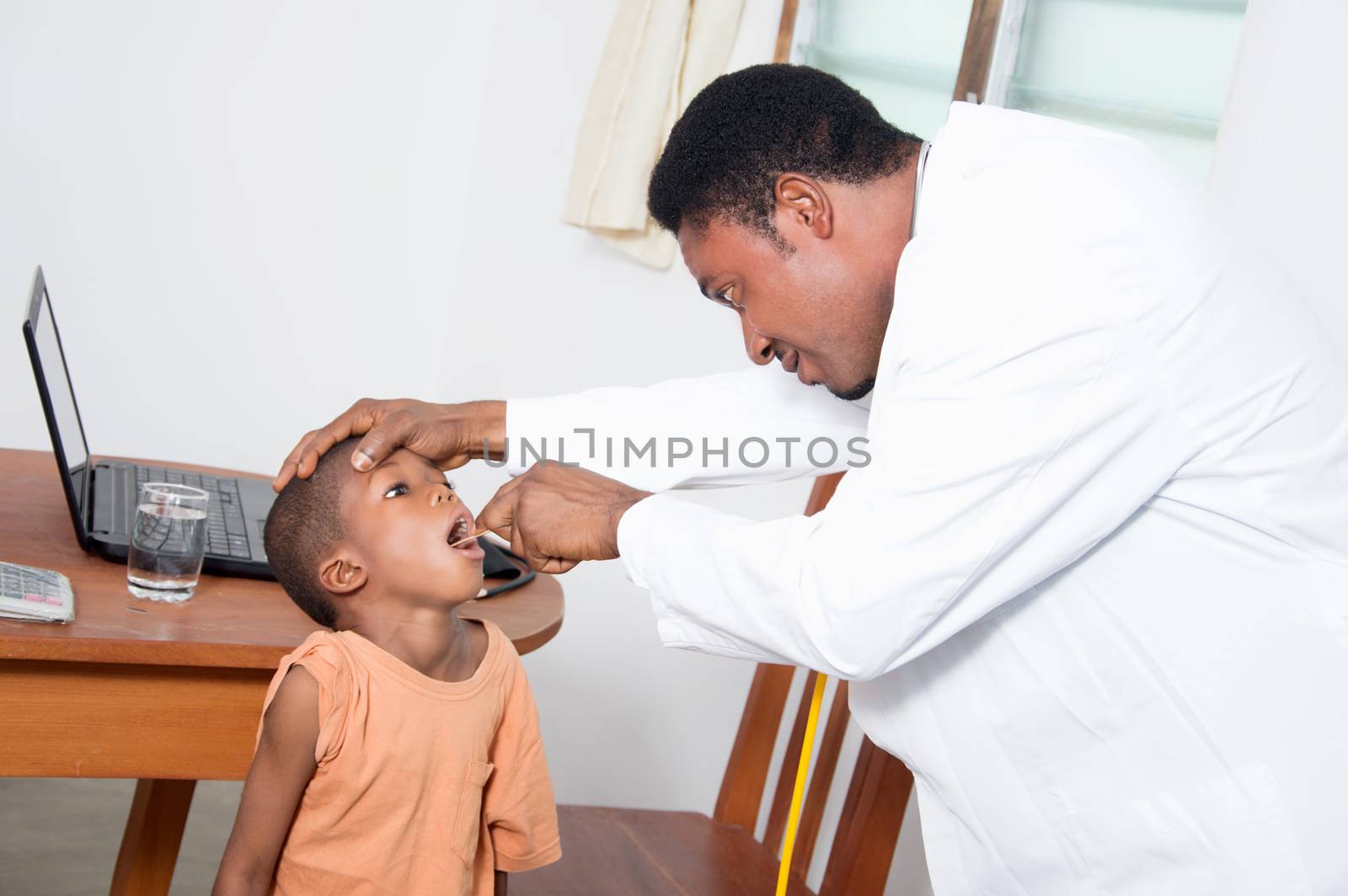 The health professional examines the boy looking in his mouth.