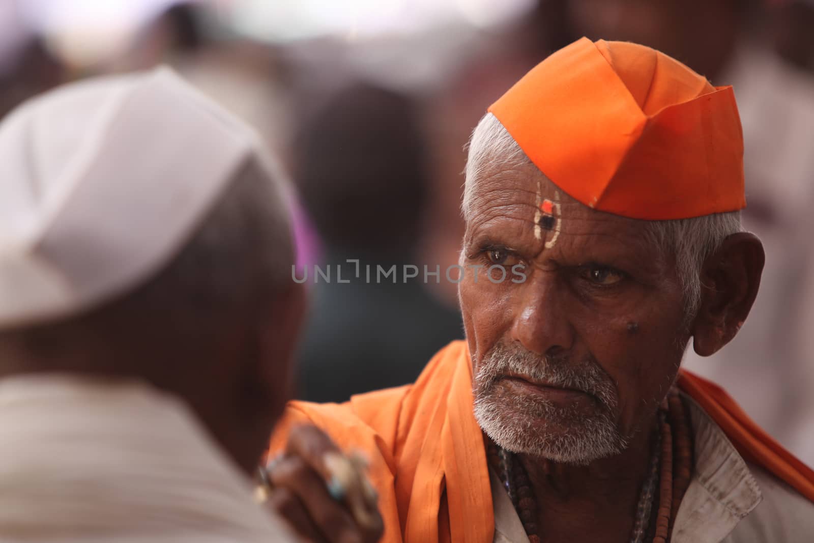An old Indian hindu pilgrim wearing traditional hat in the hindu saffron color.