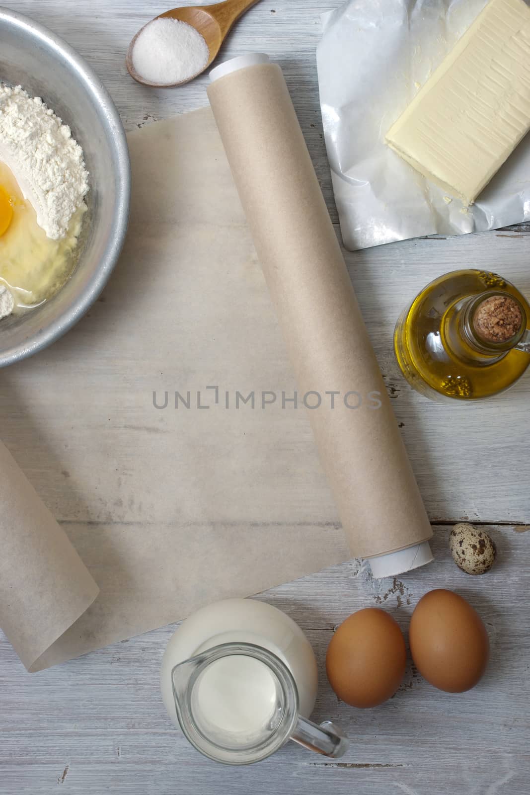 Ingredients for the pancakes on the white wooden table around the parchment roll 