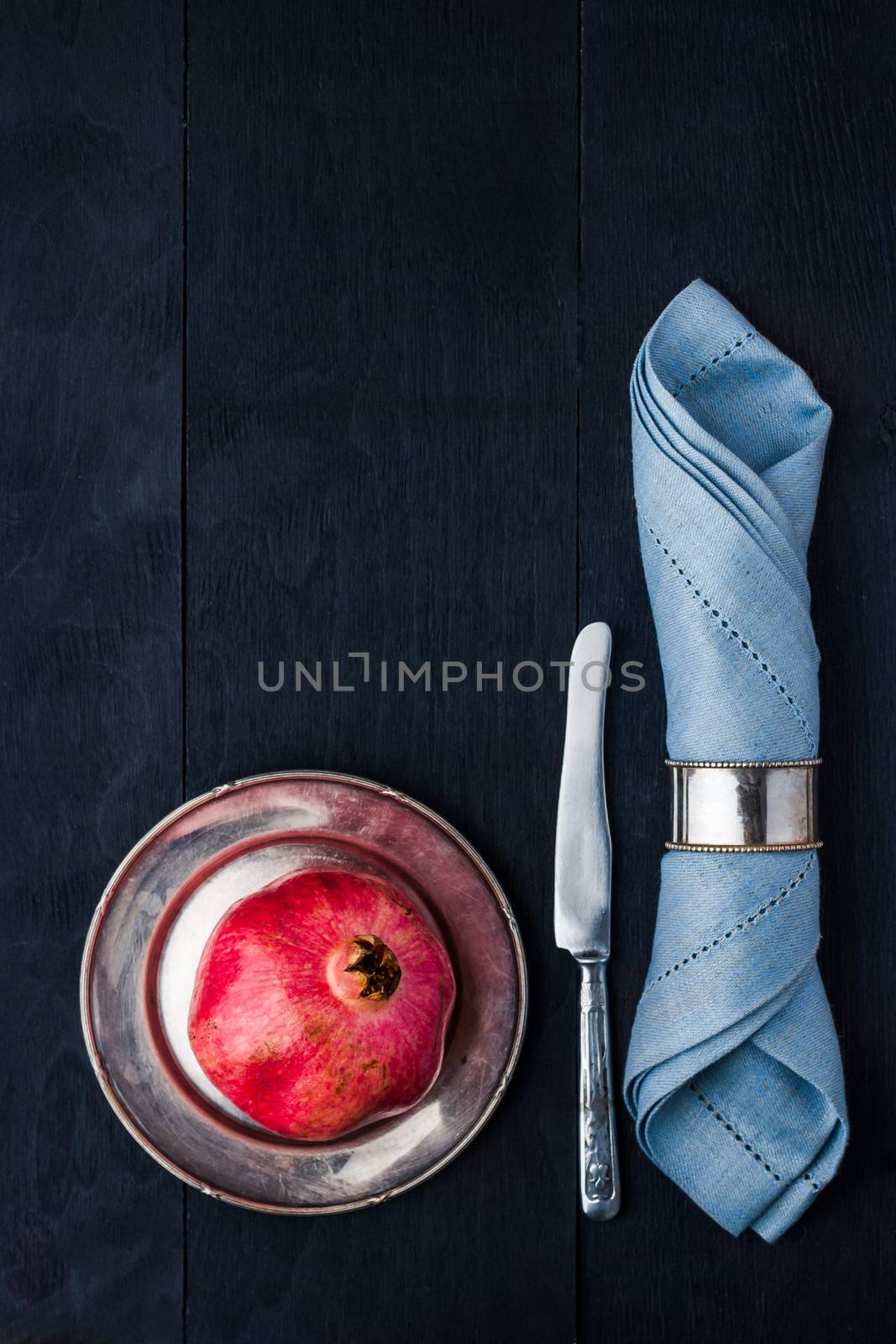 Pomegranate  on the vintage metal plate with knife and napkin vertical