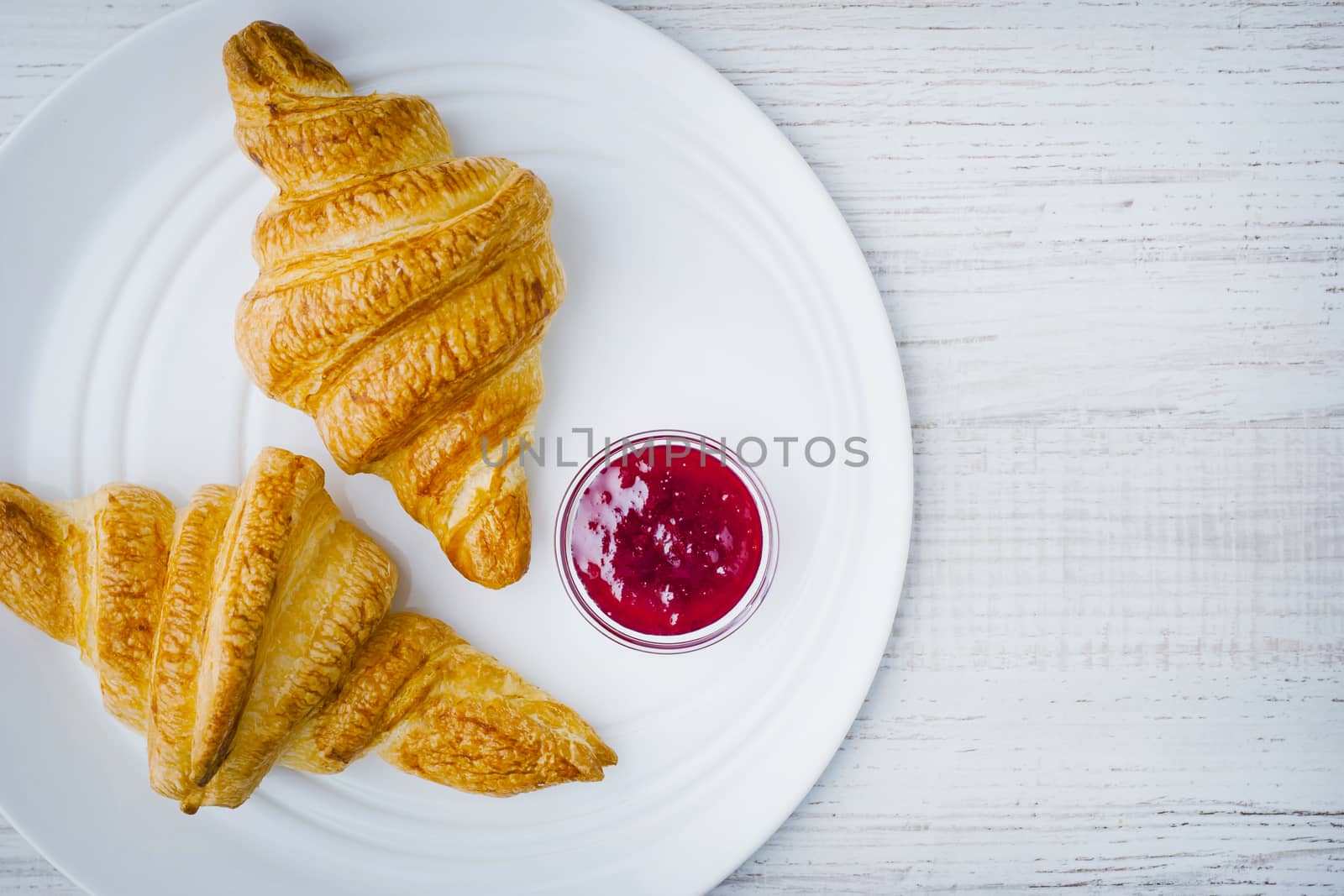 Croissants and  jam on the white ceramic plate top view