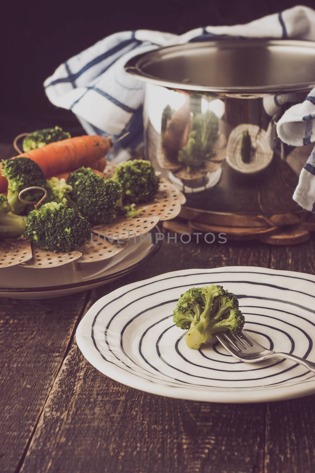 Steamed vegetables with broccoli on a fork on the wooden table