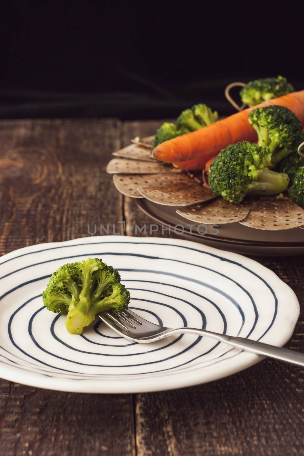 Steamed broccoli on a fork on the ceramic plate vertical