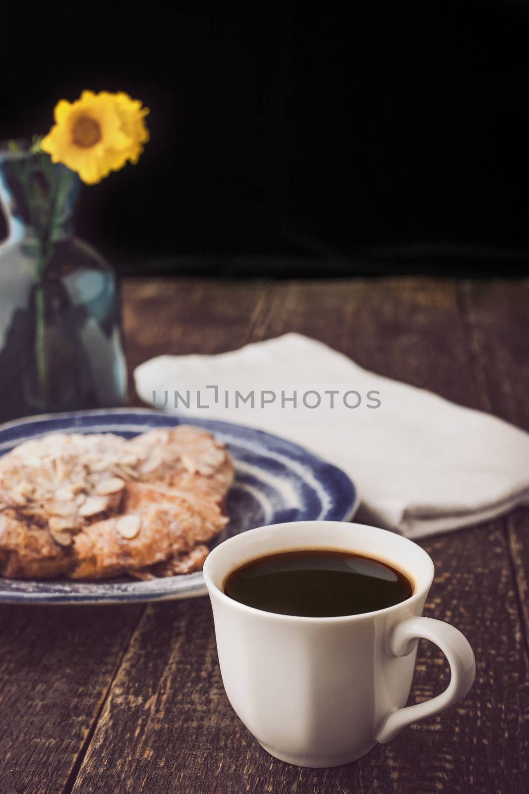 Cup of coffee with blurred croissant  and flower vertical
