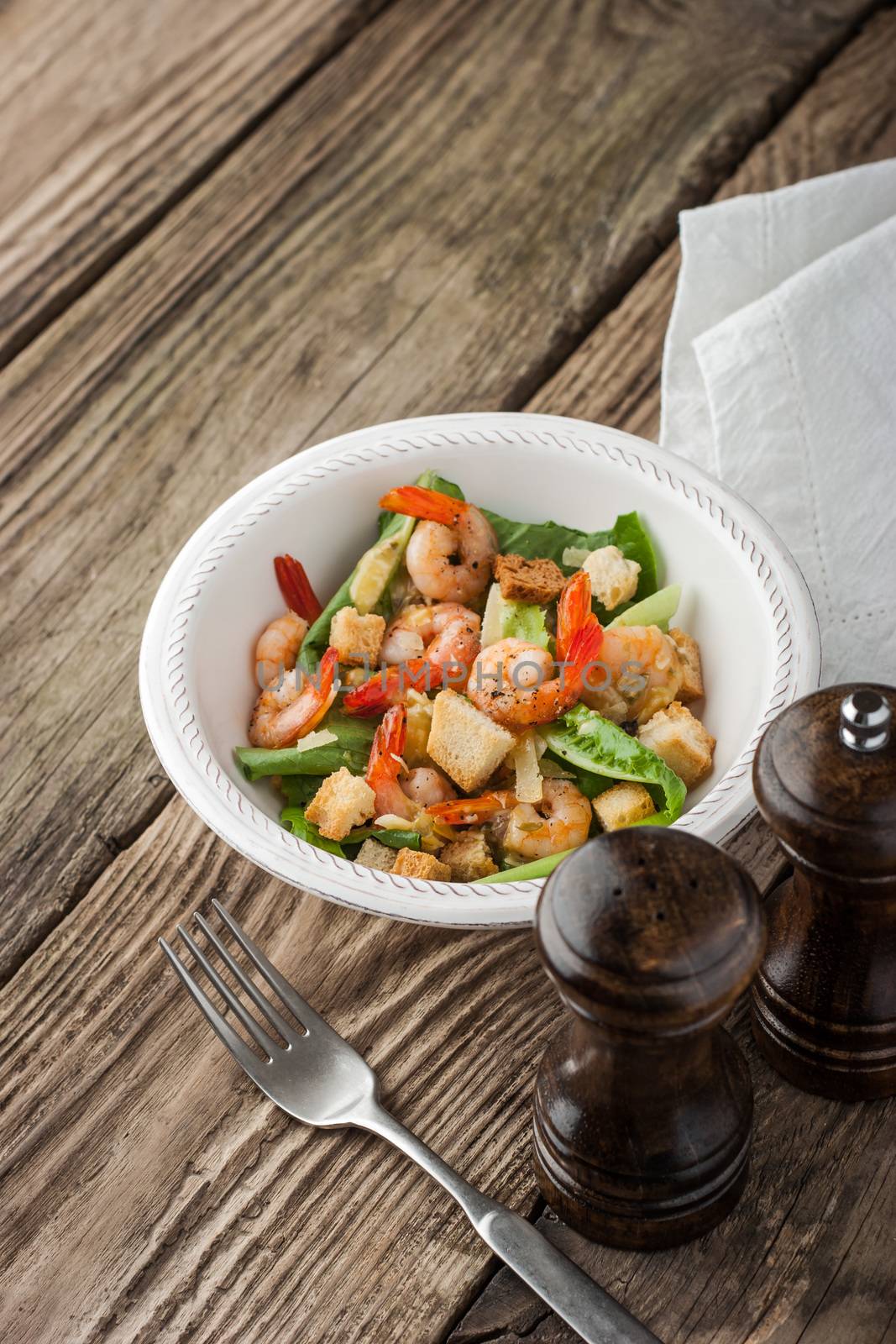 Shrimps Caesar salad with fork by Deniskarpenkov