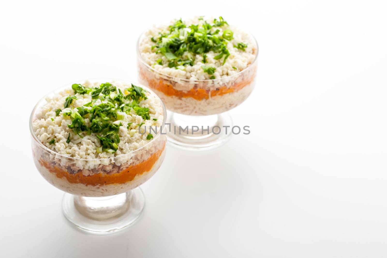 Layered salad with eggs and fish on the glass dish horizontal