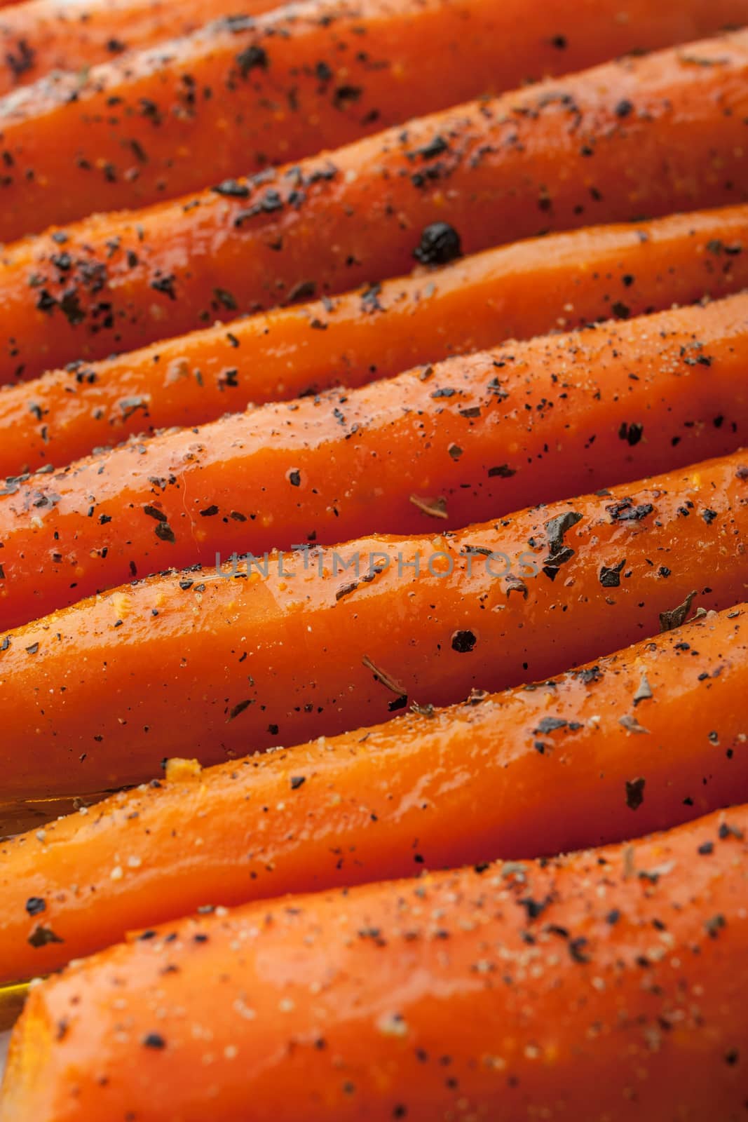 Baked carrots with black pepper and herbs  close-up background vertical