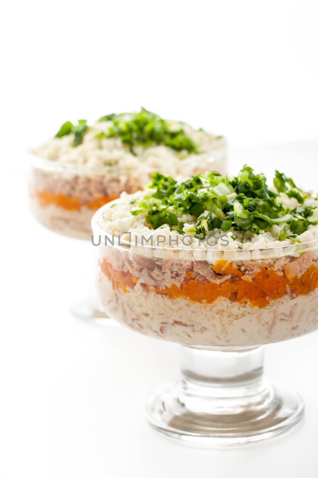 Layered salad with eggs and fish on the white background vertical