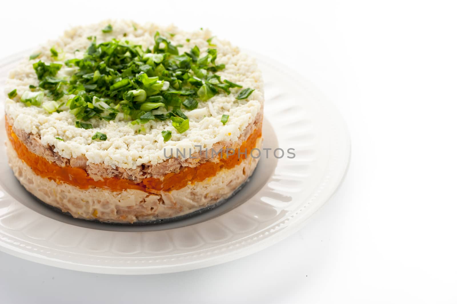 Layered salad with eggs and fish on the white background