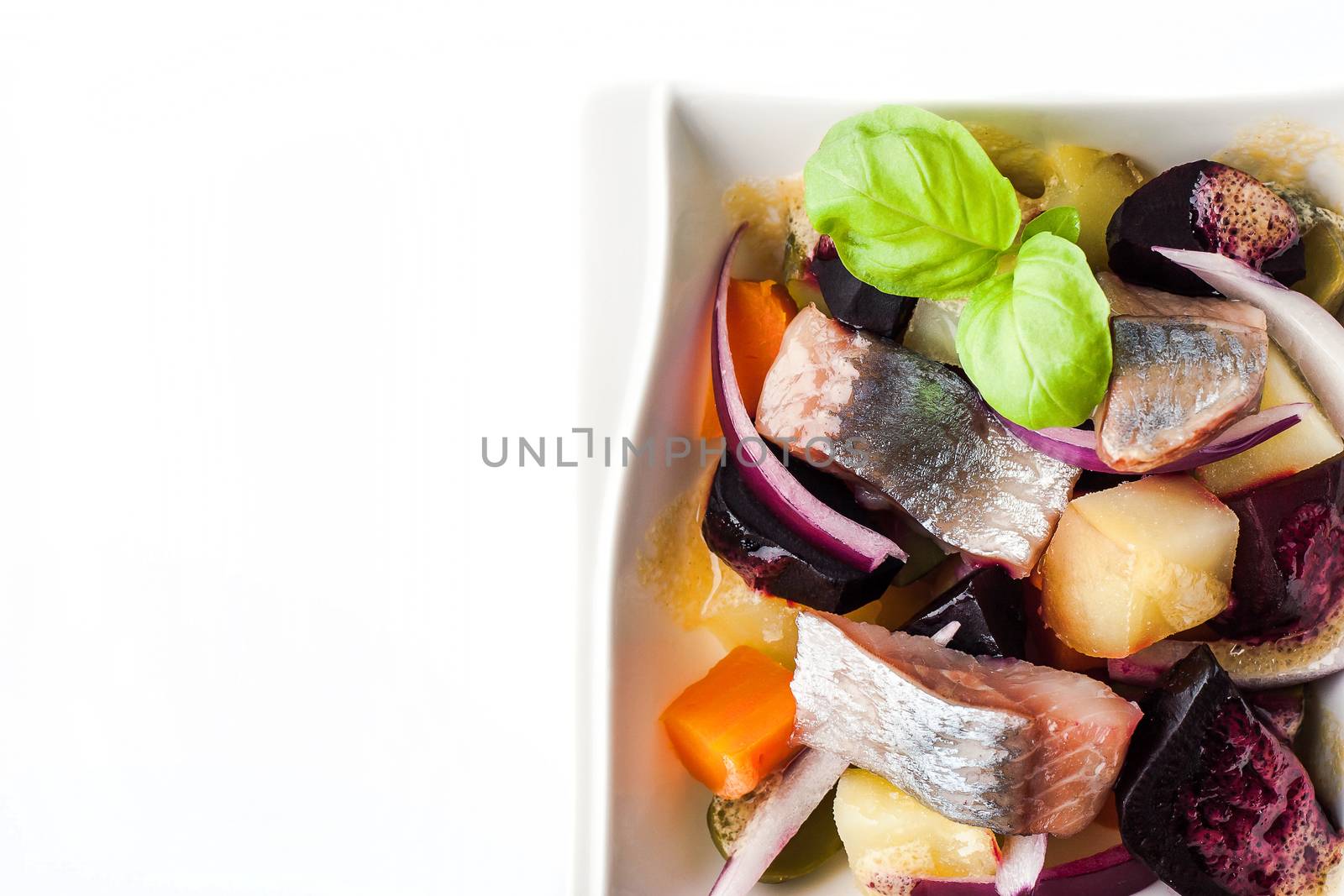 Vegetable salad with herring on the white background top view