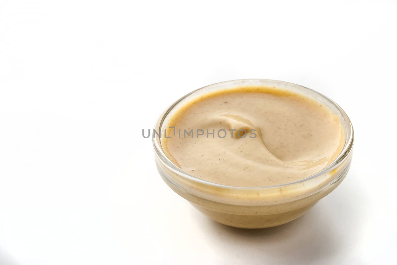Mustard on the glass dish on the white background