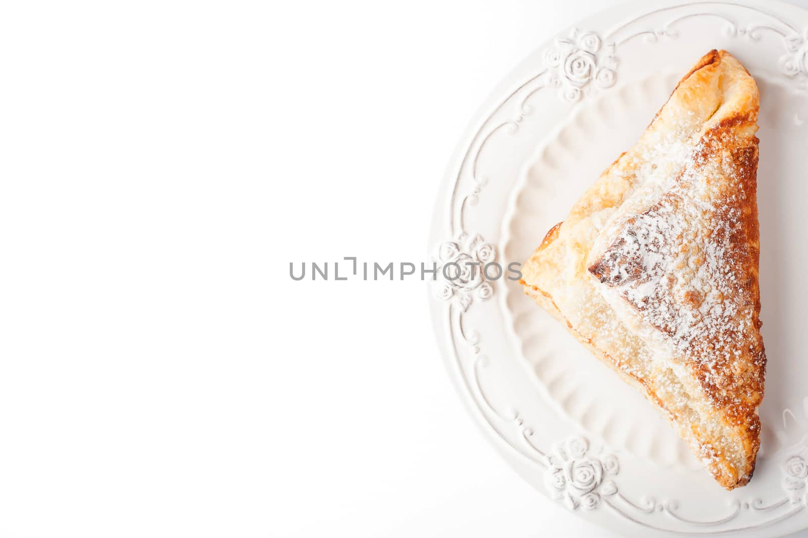 Cream puff with powdered sugar on the white plate top view