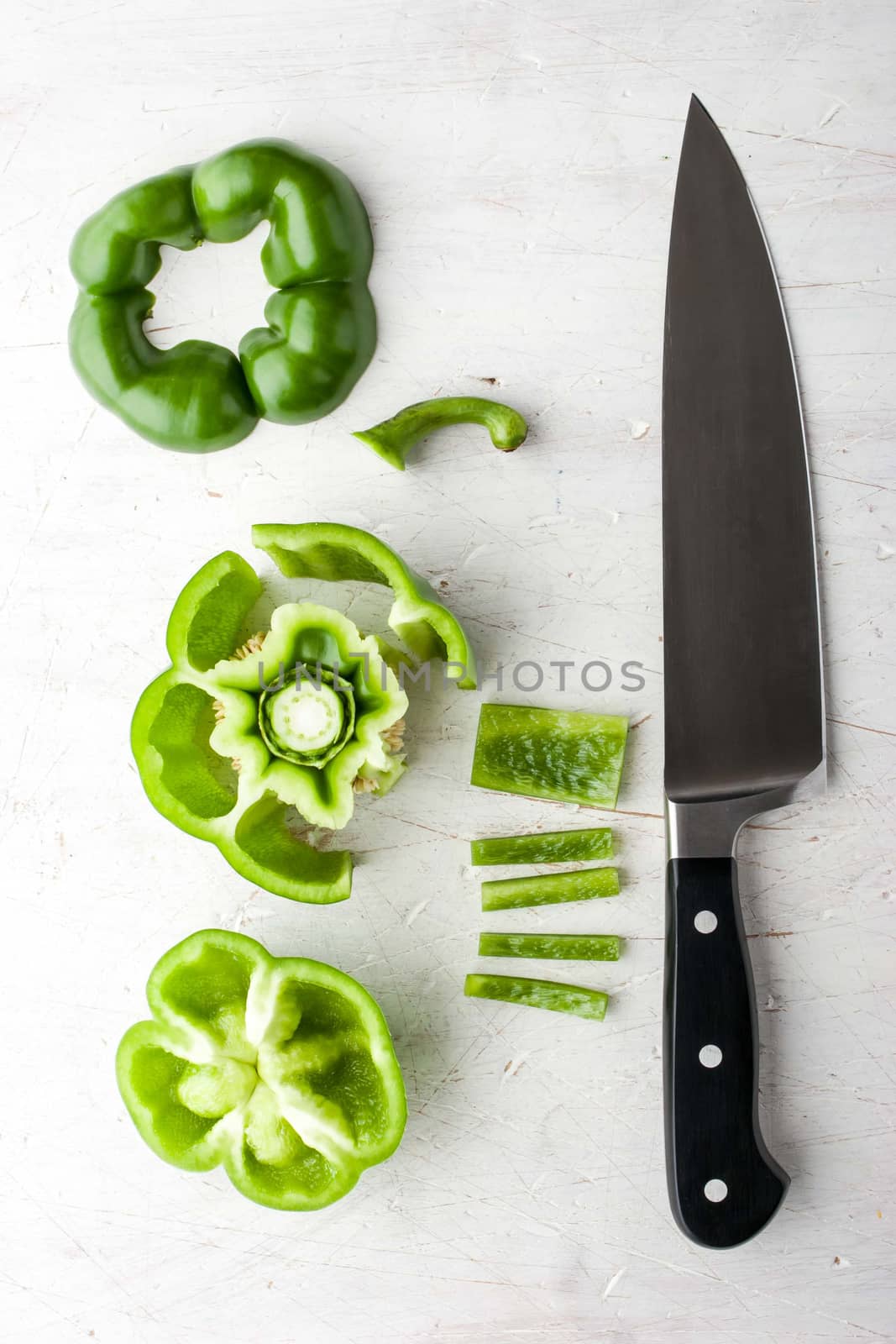 Sliced sweet pepper with knife on the white table vertical