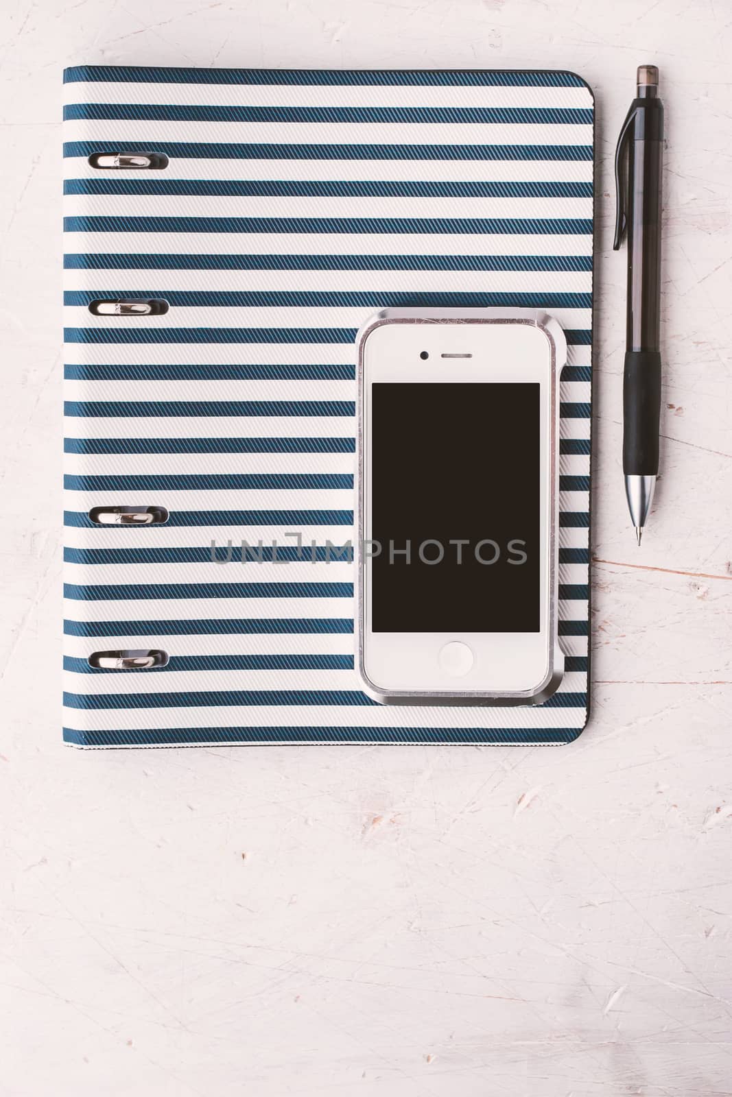 Notebook with pen and telephone on the white table vertical