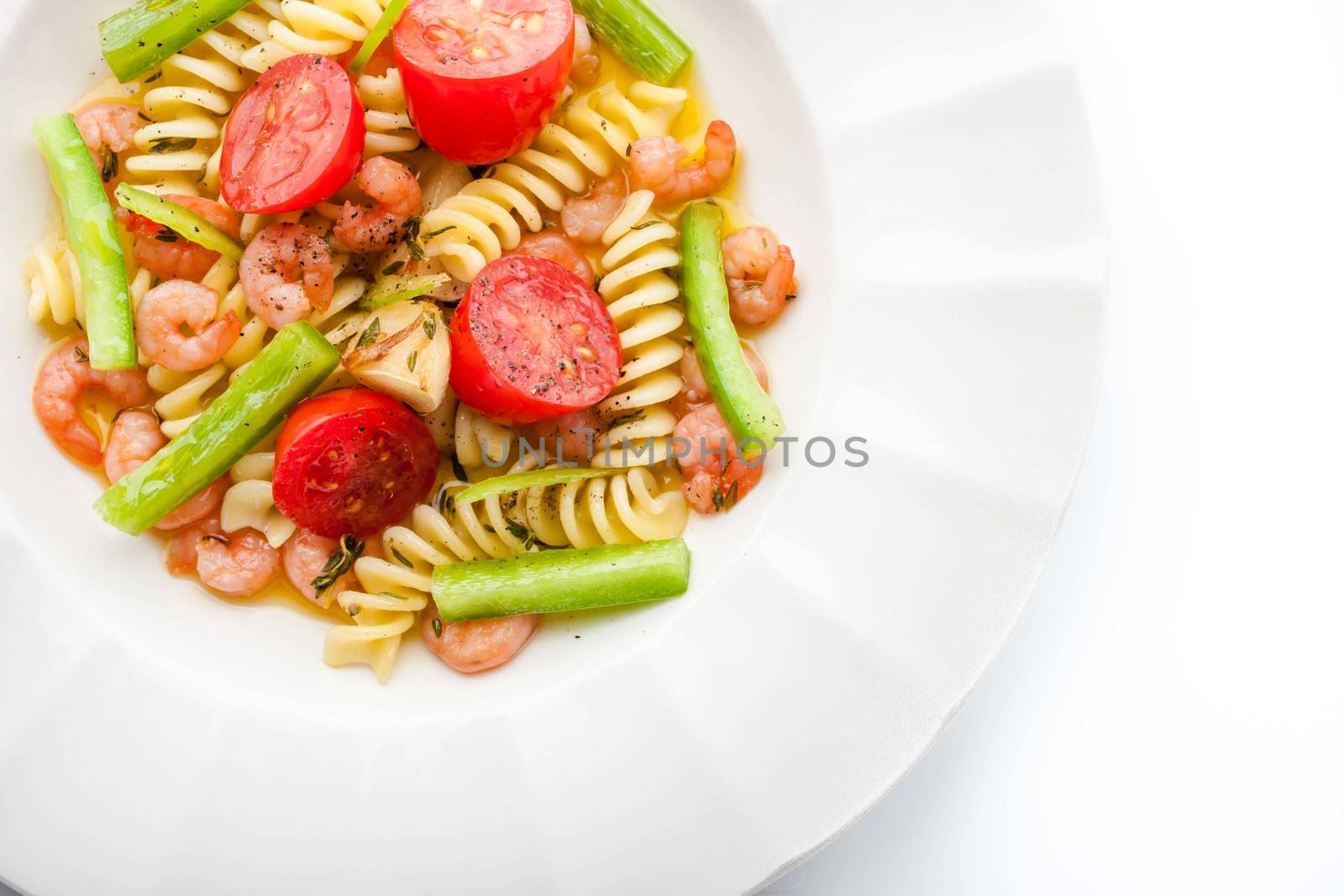 Pasta with vegetables and prawns on the white plate top view