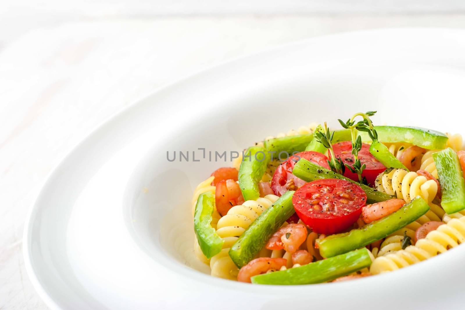Pasta with vegetables and shrimps on the white plate horizontal