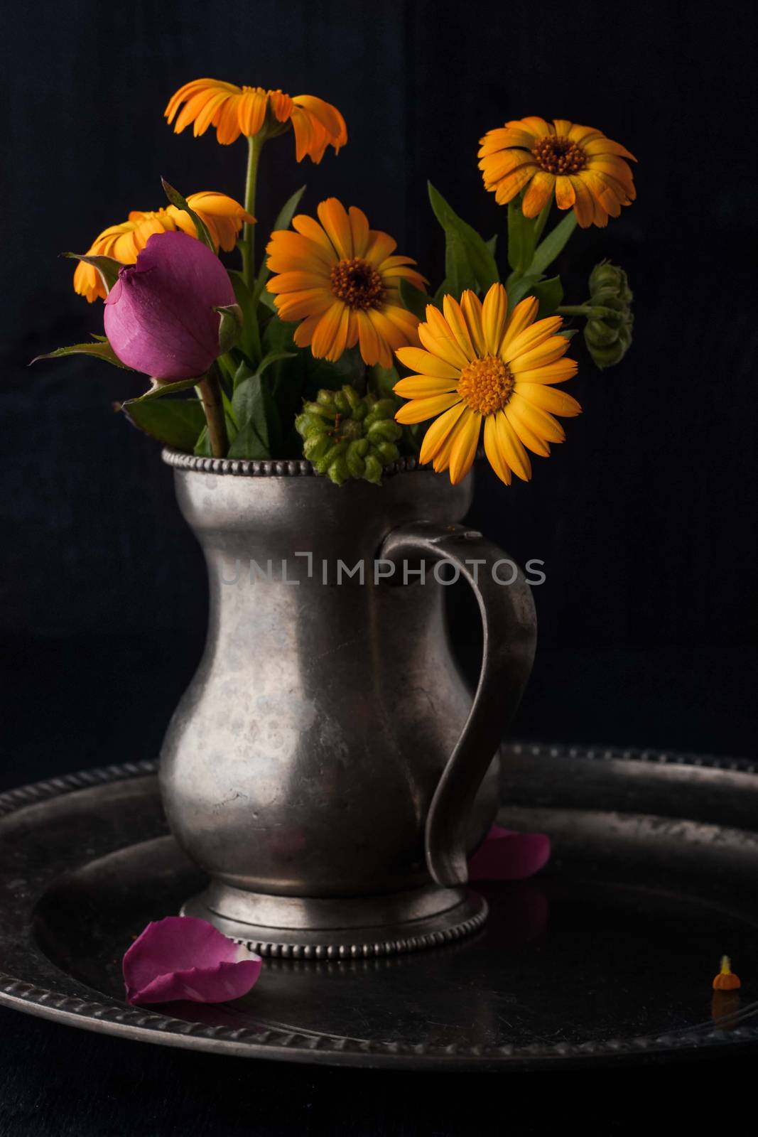 Bouquet of flowers in the old metal jug vertical