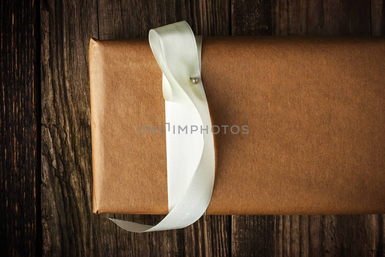 Homemade gift with white ribbon on the wooden background
