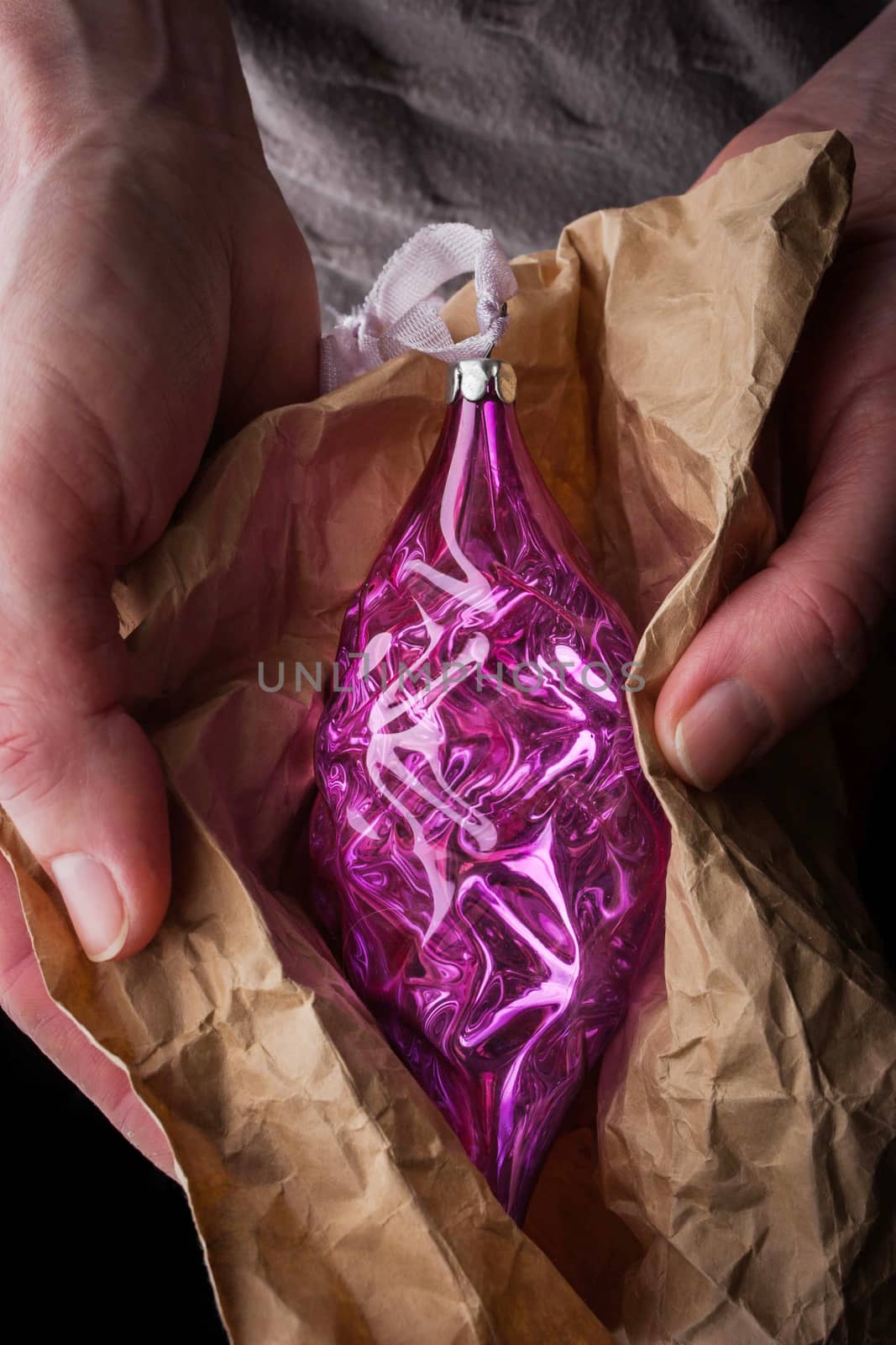 Christmas tree decoration in wrapping paper in the hands vertical