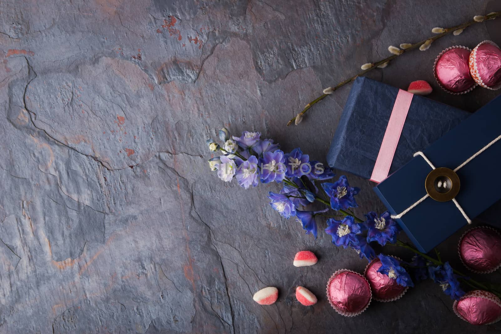 Spring gift with candy and flowers on a blue stone background horizontal