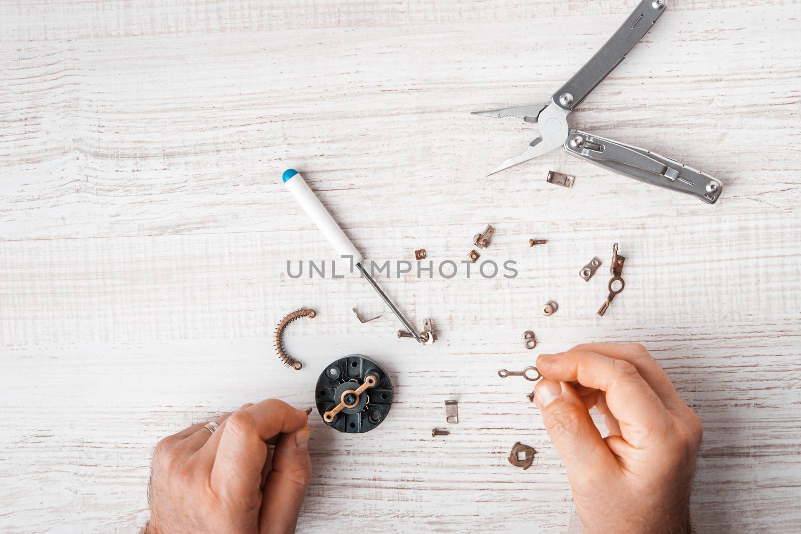 Workers assemble a mechanism with a screwdriver and pliers horizontal 