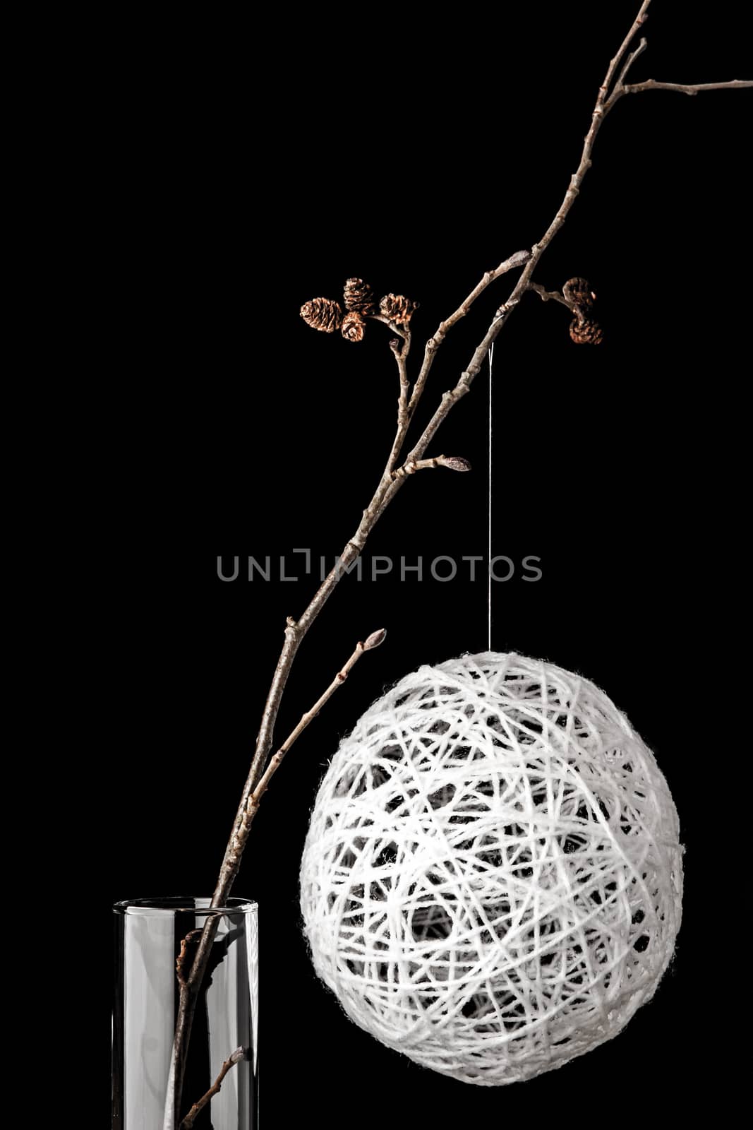 Alder branch in the glass with a white christmas ball vertical