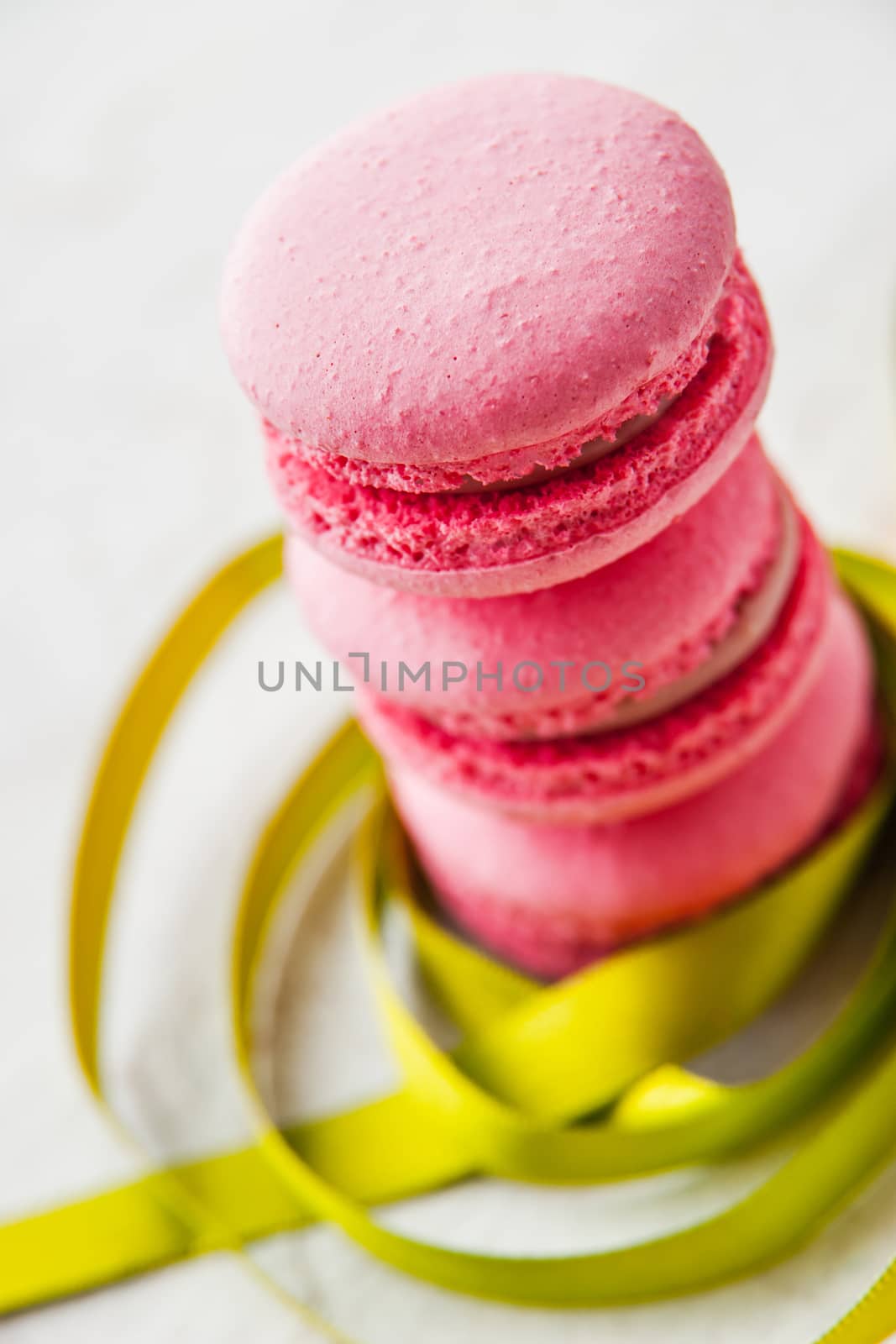 Pink macaroon on a white background with green ribbon vertical