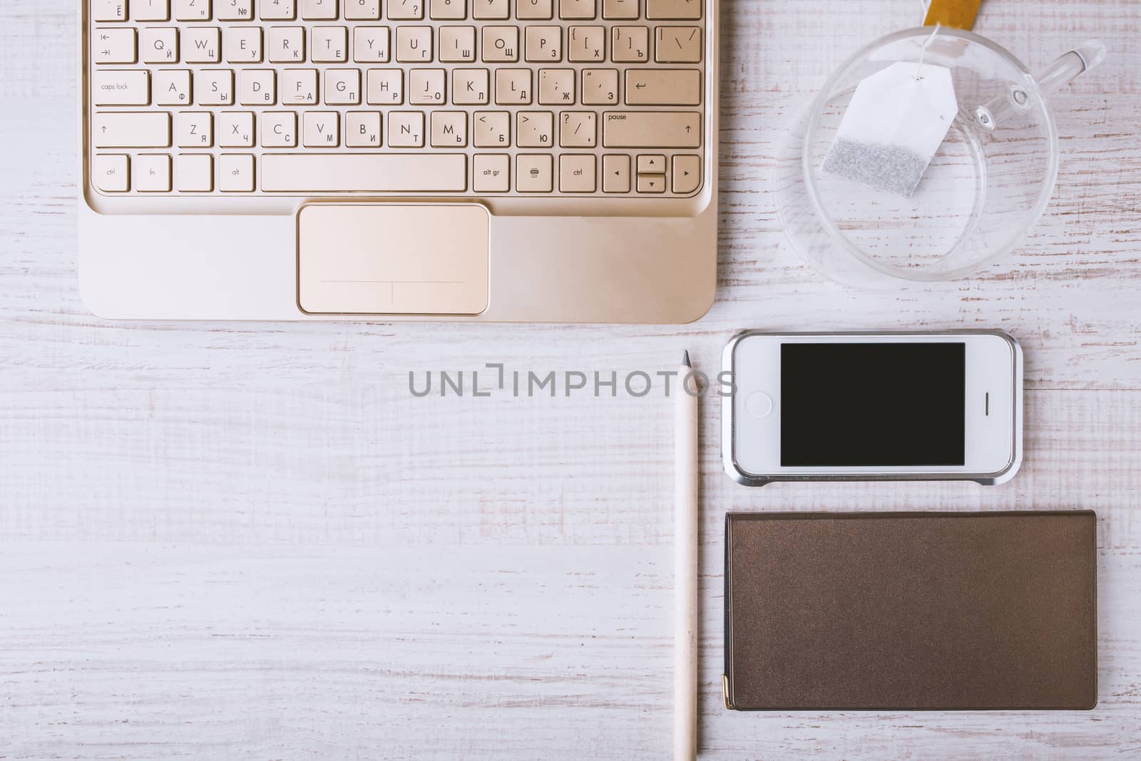 Laptop, mobile phone, notebook, cup on a wooden table horizontal