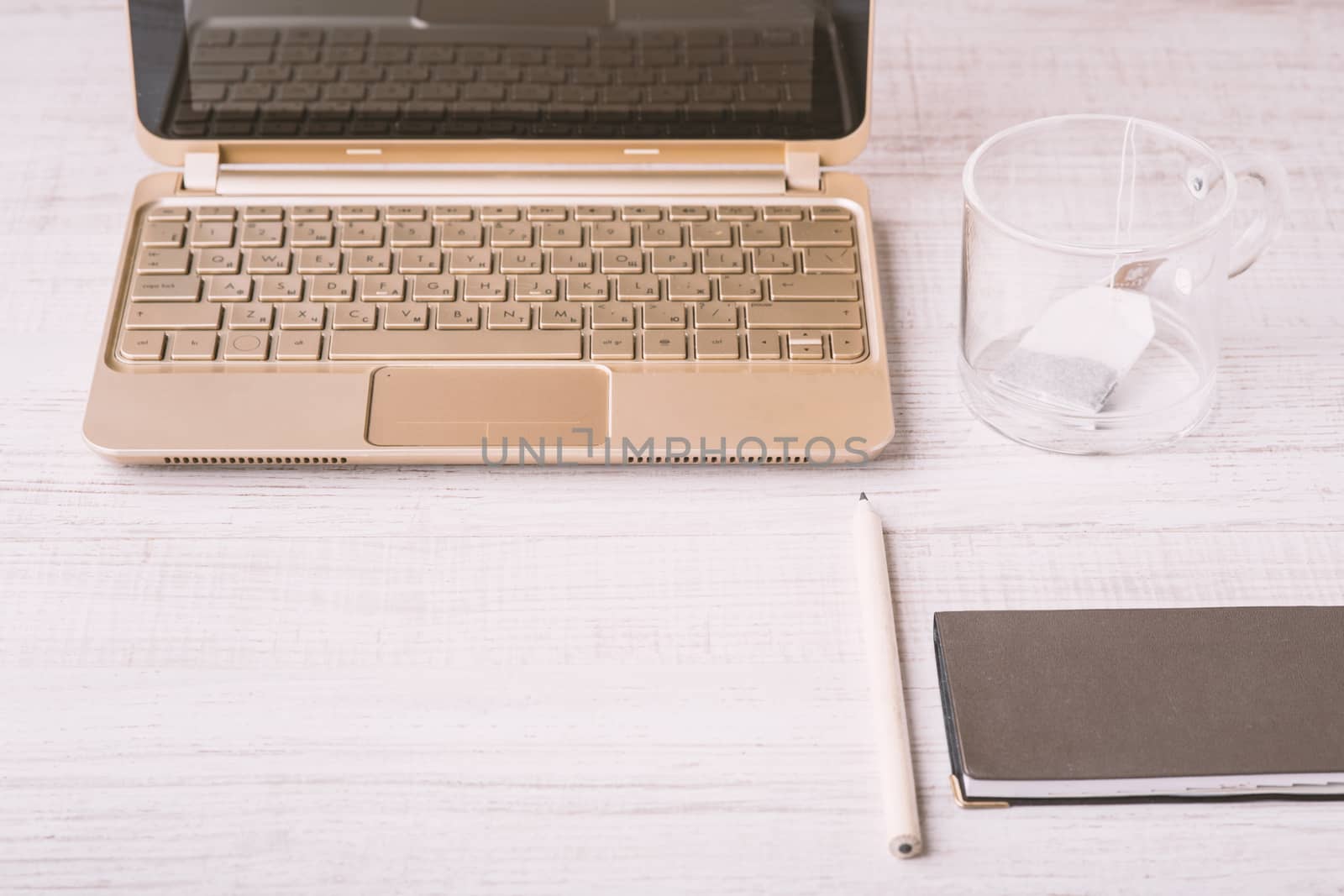 Laptop and notebook and a cup on a wooden table horizontal