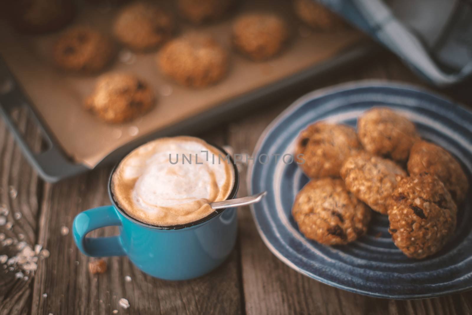 Baking tray and a plate of oatmeal cookies on the wooden table horizontal