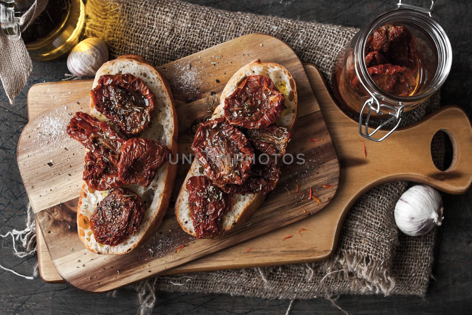 Sun-dried tomatoes on the white bread on the wooden board top-view horizontal