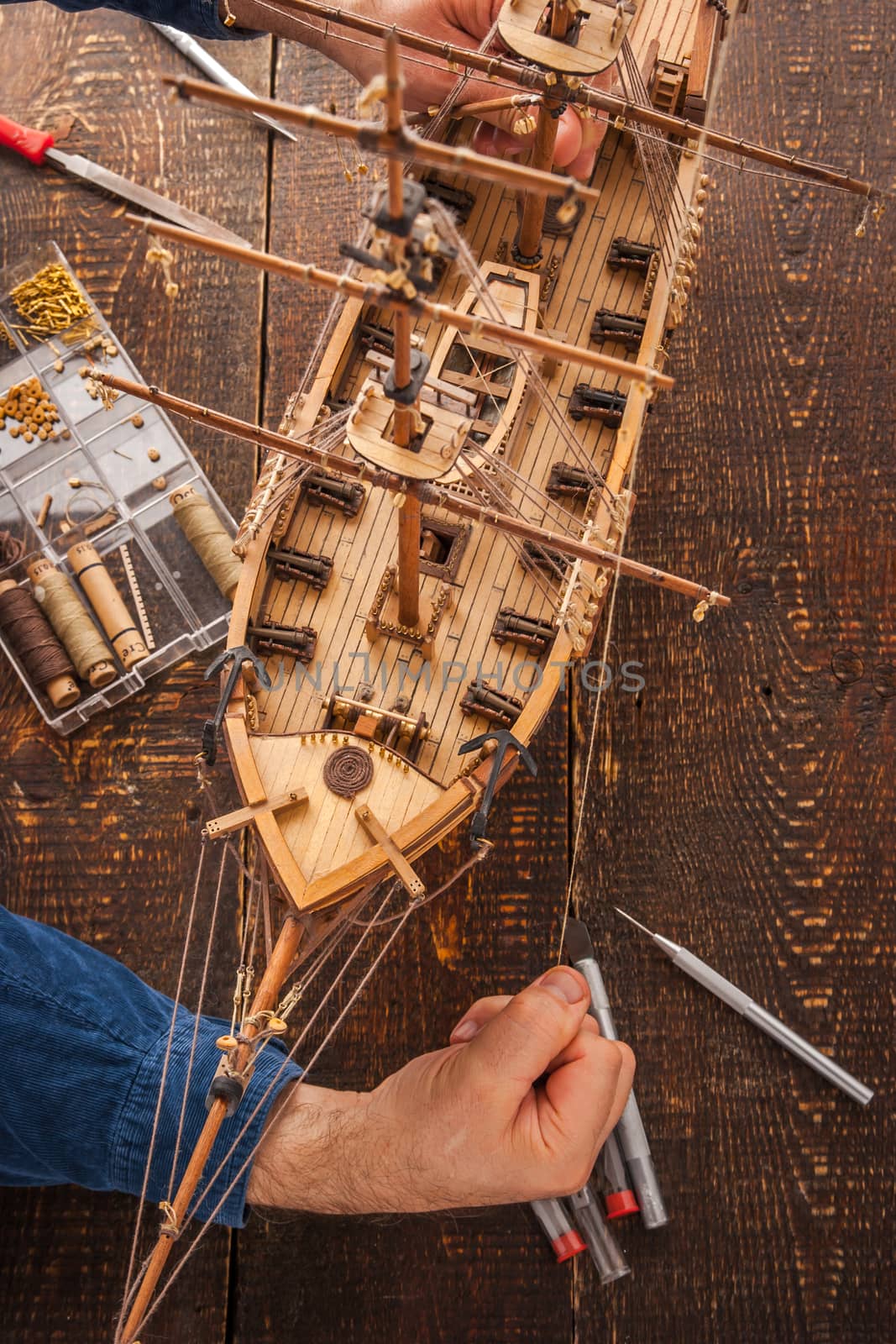 Man collects the vehicle model on the wooden table vertical