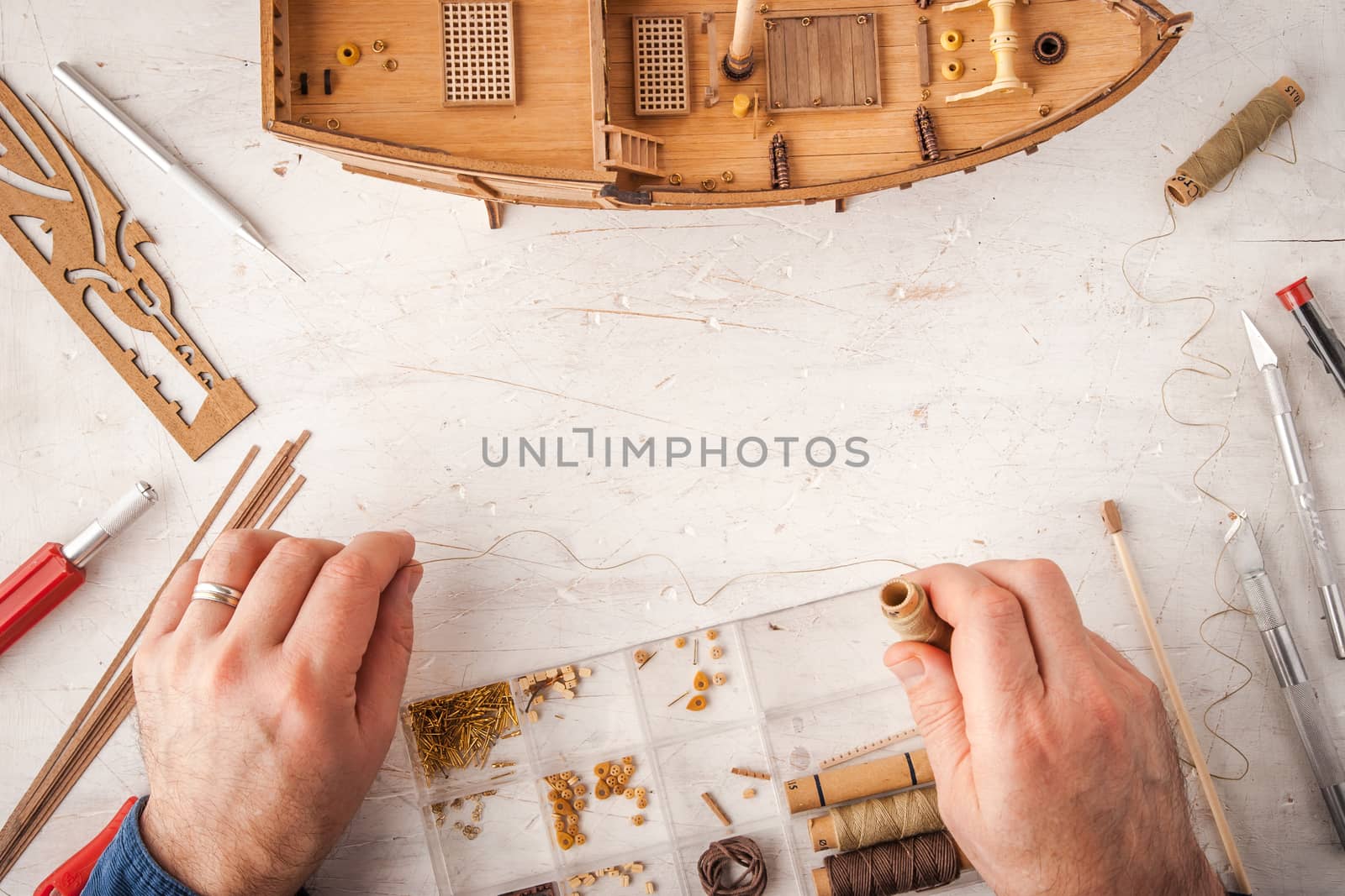 Man collects ship model on a white table horizontal