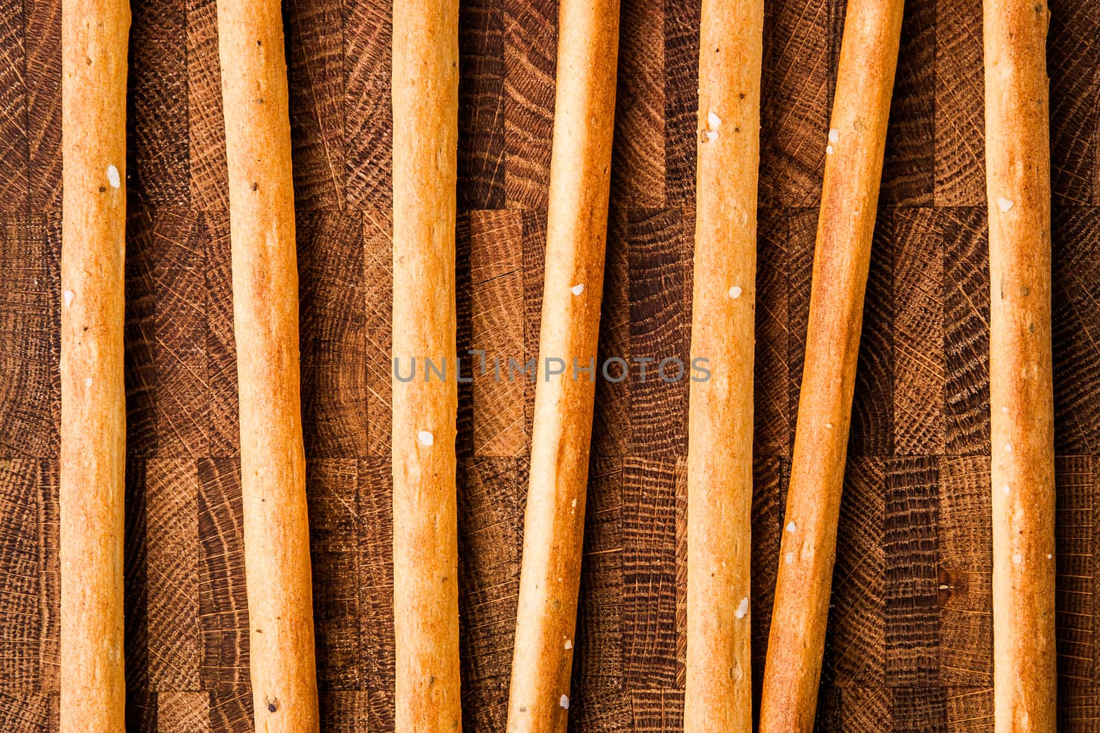 Salted bread sticks lie on a chopping boar horizontal