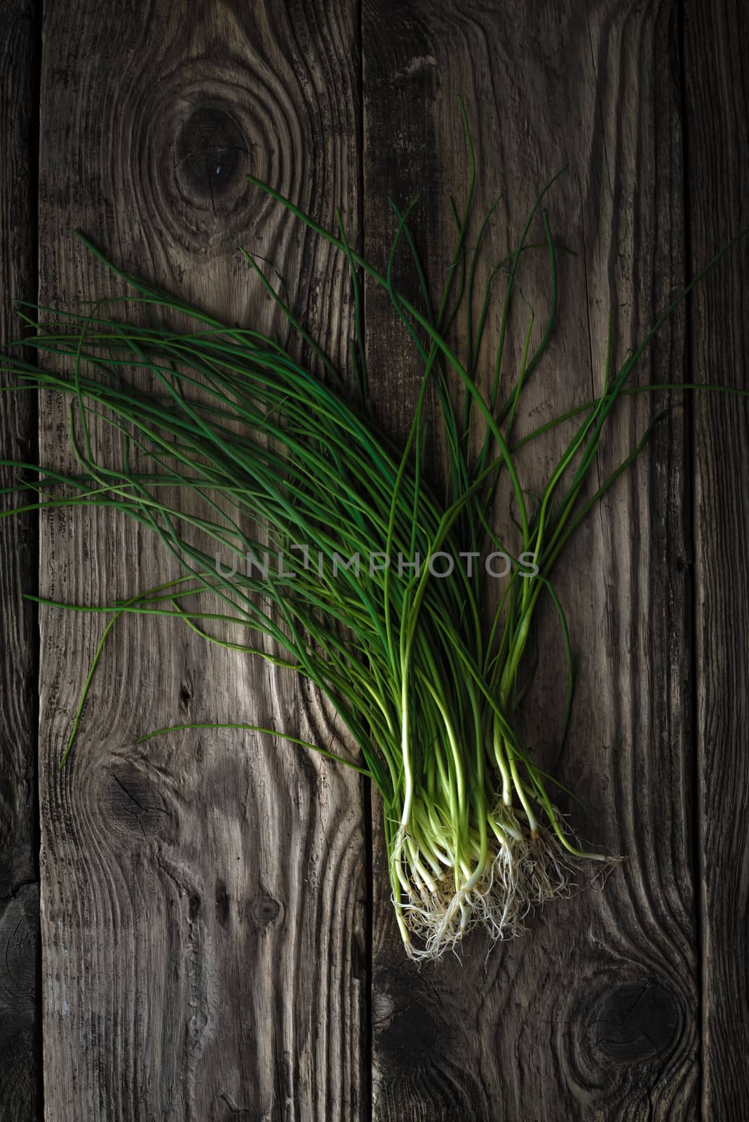 Stalks of green onions on a wooden table vertical