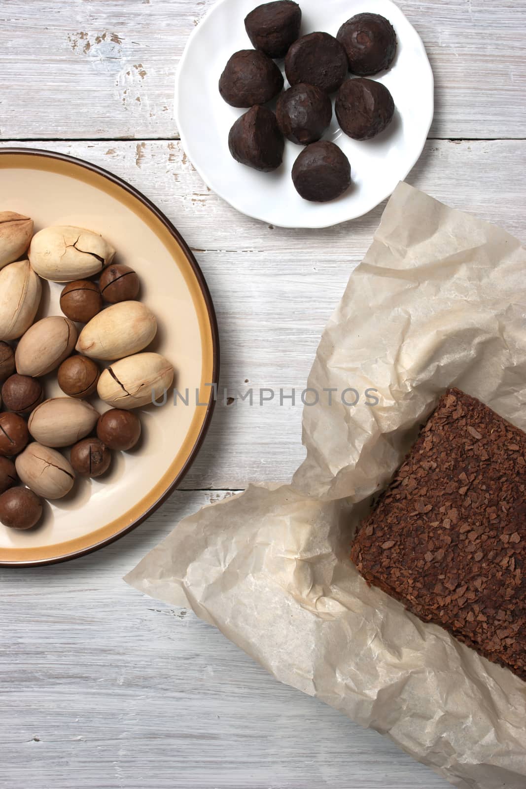 Nuts, truffle candy and chocolate cake on the white background by Deniskarpenkov