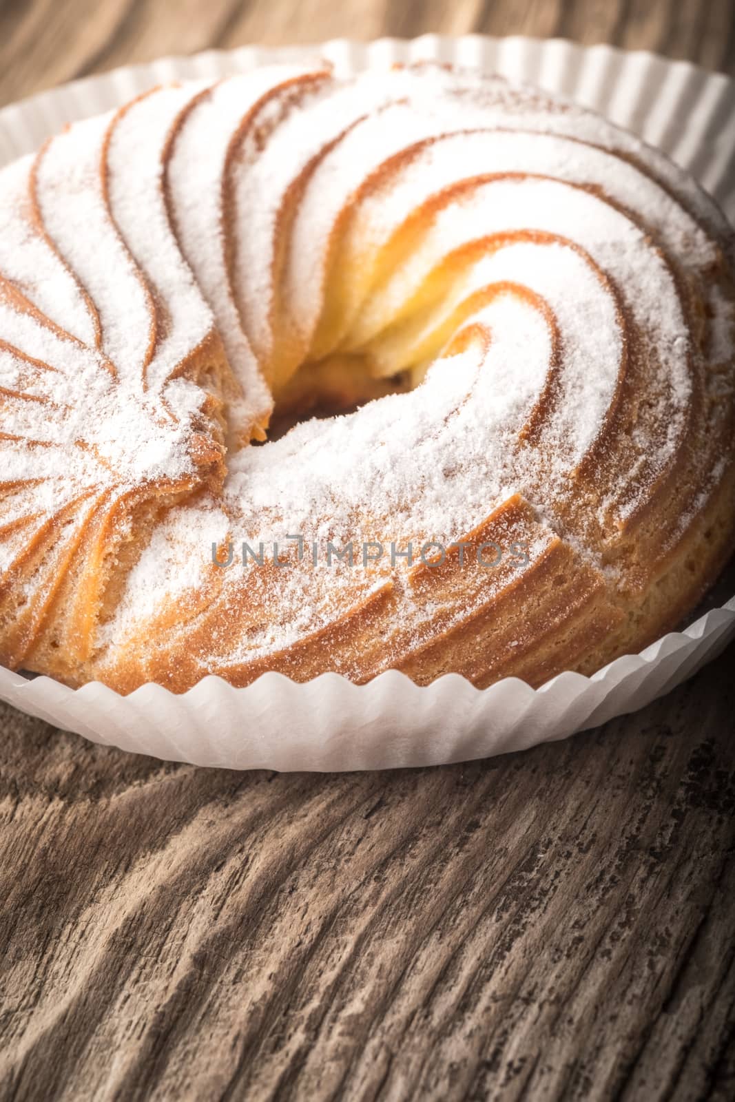 Cake in powdered sugar on a wooden table by Deniskarpenkov